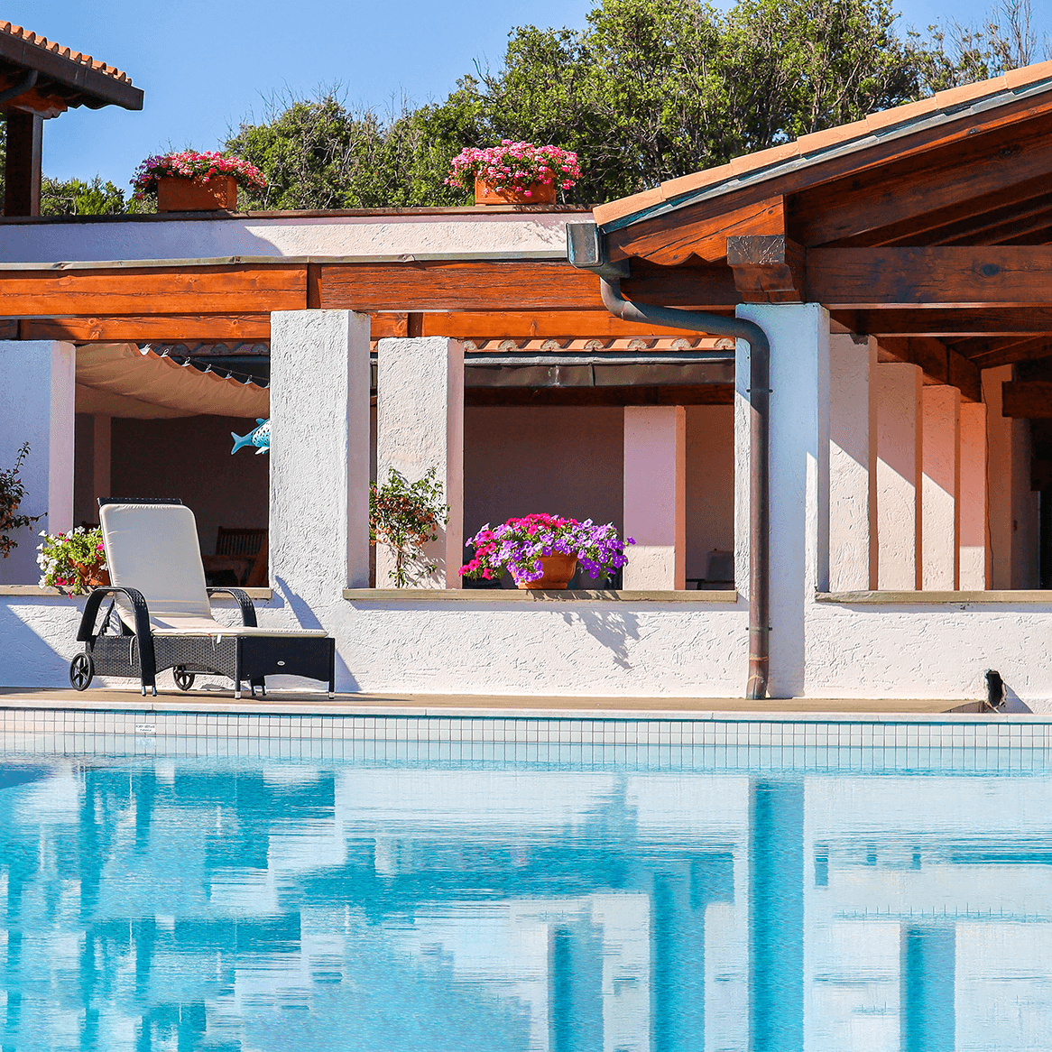Villa Levante stile classico toscano con Portico e sdraio davanti a piscina a sfioro e vaso di fiori 